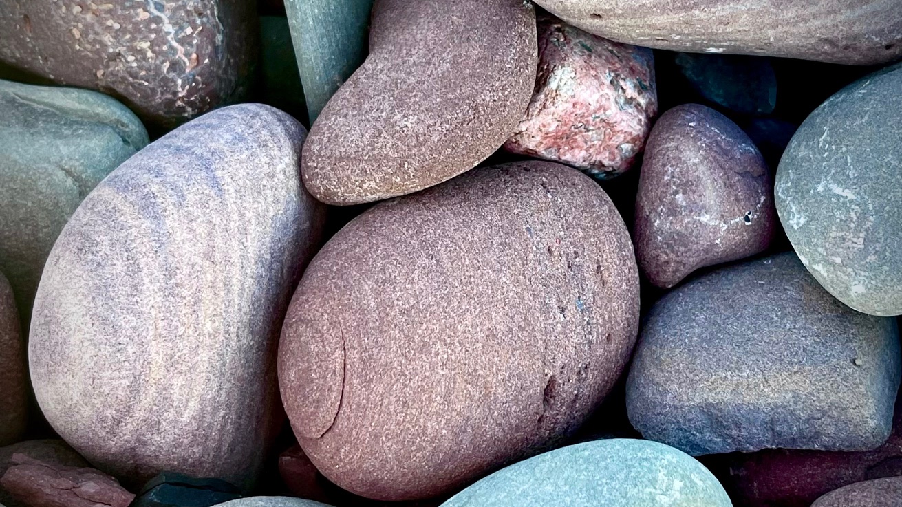 Smooth shoreline stones in muted reds, mauves, and blue-greens
